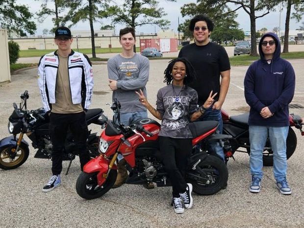 A group of students of different heights standing with training motorcycles