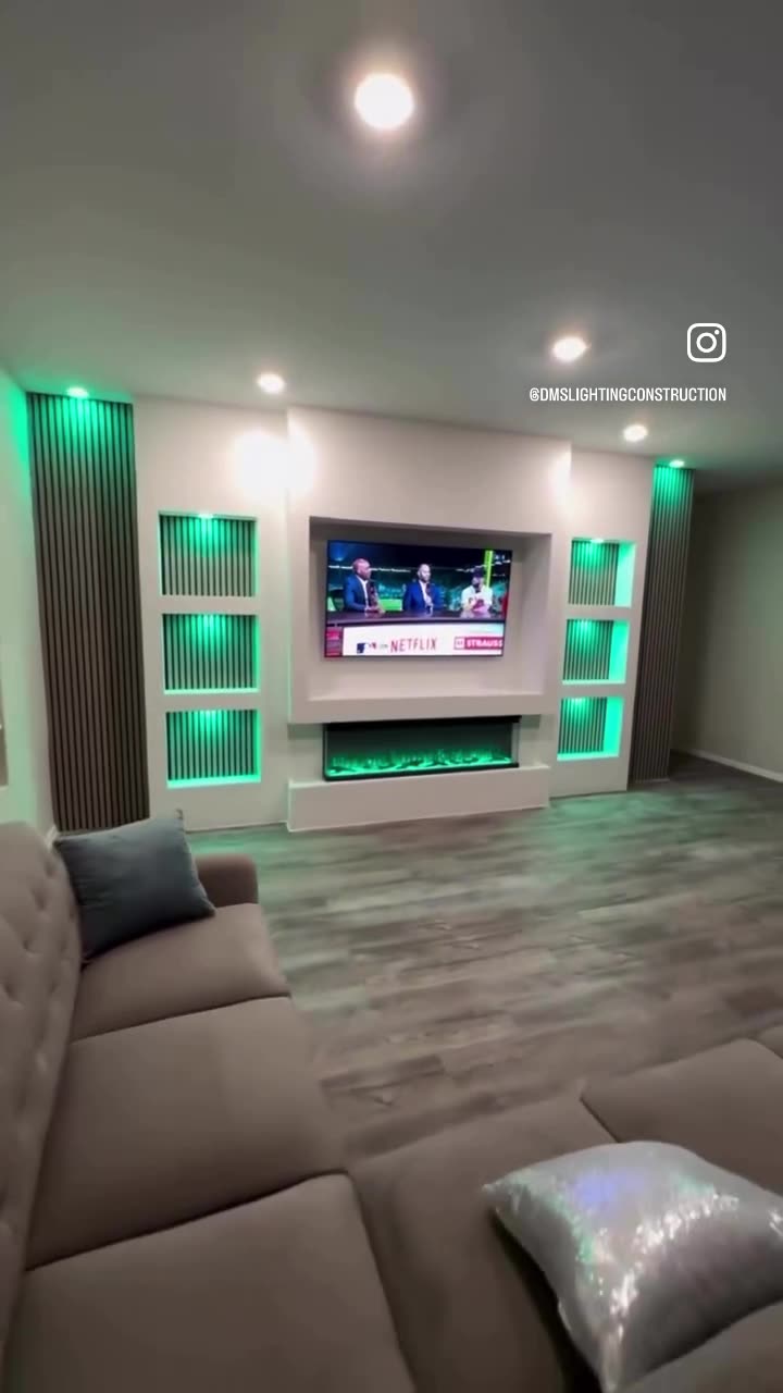 Finished media wall with backlit niches, fluted panels and a linear fireplace lit green